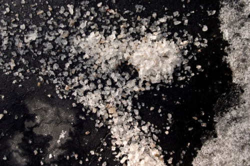A photo of road salt scattered on a wet winter road.